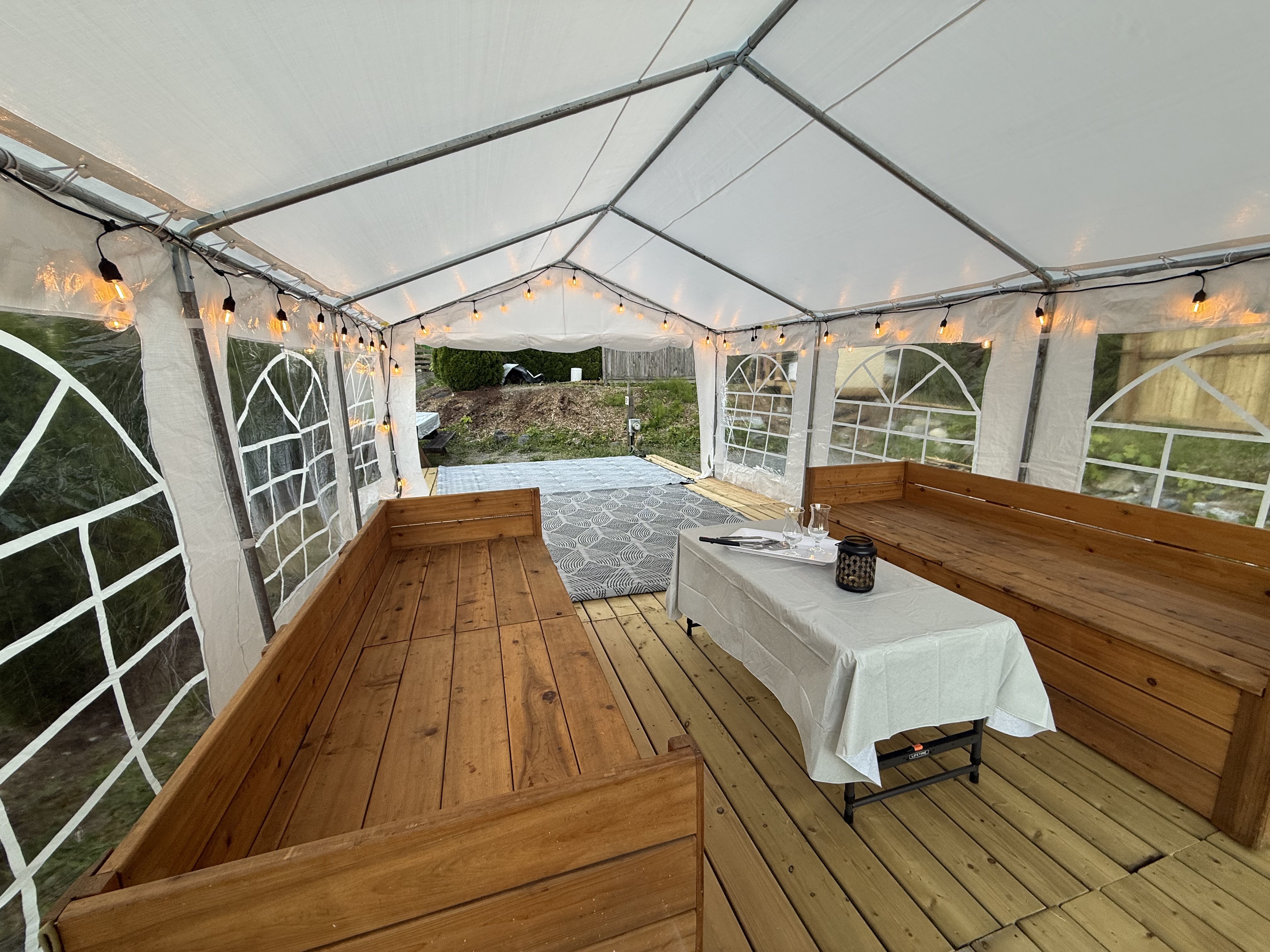 Built-in wood bench seating and a table set under the covered tent